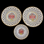 Conjunto de três pratos de porcelana. Apresenta borda fenestrada e centro com decoração floral. No verso as inscrições: 572 Modra SL. Made in Slovakia. 27 cm e 19 cm. 