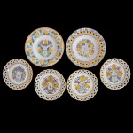 Conjunto de seis pratos de porcelana. Apresenta borda fenestrada e centro com decoração floral predominando as cores amarela. No verso as inscrições: 573 Modra + H.K. Made in Slovakia. 24 cm e 19 cm. 