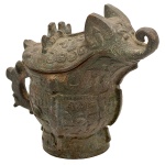 Vaso ritual chinês em bronze, para vinho, no formato de elefante, ornamentado em alto relevo por adornos geométricos estilizados. Corpo bojudo encimado por tampa com cabeça. Peça semelhante às da dinastia Shang (c. 1600 1046 a. C.). Séc. XX. 18 x 16 x 11 cm.