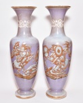 Par de vasos em opalina de tom lilás, decorado por cena épica em esmaltagem monocromática dourada, encimada por circundado de arabescos. Verso decorado por escudo de armas. Europa. Final do séc. XIX. 45 cm.