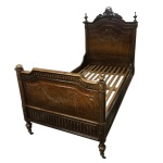 Cama portuguesa em madeira lustrada, esculpida e ornamentada em estilo neoclássico com guirlandas, frisos geométricos e florões. Cabeceira em arco encimada por adorno floral vazado. Portugal. Séc. XIX. 155 cm (alt. da cabeceira). 2.15 x 1.10 cm.