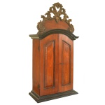 Oratório brasileiro D. José em madeira lustrada, com frontão arqueado, encimado e ornamentado por adorno vazado com volutas e folhagens. Caixa retangular com par de portas almofadadas revelando interior com friso à volta e fundo pintado com estilizações sobre fundo azul celeste. Séc. XVIII. 120 X 59 X 23 CM.