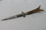 Bela faca com cabo de servo sem a bainha. Na lâmina existe a figura de um alce. Mede no total aproximadamente 27 centímetros.
