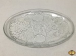 Travessa oval em vidro moldado com frutas em relevo. Medindo 33cm x 21,5cm.