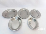Jogo 5 travessas em aço inox . Sendo uma travessa redonda medindo 26cm de diametro, 1 travessa oval pequena medindo 25x18cm de comprimento, 1 travessa oval média medindo 30x21cm de comprimento, 1 travessa oval pequena funda, medindo 20x14cm de comprimento e 1 travessa oval média funda, medindo 23x17cm de comprimento. Possuem marcas de uso.