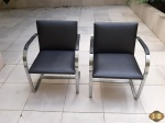 Par de cadeiras com baço em metal prateado com encosto e assento acolchoado. Medindo 50cm x 47cm x 79cm de altura.