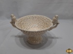 Fruteira centro de mesa em porcelana vazada com pega de aves. Medindo 18cm de diâmetro x 15,5cm de altura. Com um bicado na alça.