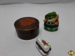 Lote de 3 caixas decorativas, sendo uma em porcelana na forma de bolsa, uma em porcelana com animais em relevo e uma em laca floral. Medindo a caixa redonda em laca 5,5cm de altura x 10cm de diâmetro. A caixa na forma de bolsa. necessita de colagem na tampa.