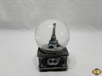 Globo de neve com torre Eiffel e caixa de música. Medindo 8,5cm x 8,5cm x 14,5cm de altura.