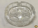 Cinzeiro em bloco de cristal ricamente lapidado. Medindo 15cm de diâmetro x 4cm de altura. Com leves bicados.