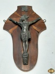 Crucifixo em metal prateado com placa em madeira. Medindo 27cm x 16,5cm, com falhas na placagem.