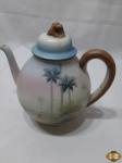 Bule de chá em porcelana com pintura de palmeiras. Medindo 17,5cm de altura.