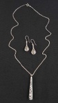 Conjunto em prata com colar e brincos com trabalho cinzelado e vazado. Med. 51 cm aberta, pingente 6 cm e brincos 4.5 cm.