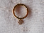 Aliança folheada a ouro, com zirconias, adornada com mãozinha judaica. (usada)