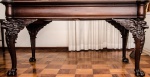 Espetacular mesa em madeira nobre com tampo recortado em cilindro nas 4 laterais, pés encimadas por águias com asas abertas para as laterais, pés de garra com 2 gavetas com chaves. Tamanho: 161 x 81 x 83,5 cm.