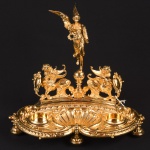 WMF - Extraordinário e Raro Tinteiro de mesa alemão Séc. XIX estilo Luiz XVI, em metal ormulu (banh ouro 24k), base em forma de concha, alçado c/ escultura de animais alados tendo ao centro Alegoria a Vitoria, saias peroladas, med. 33 x 20 x 31cm. (faltam os recipientes de cristal).