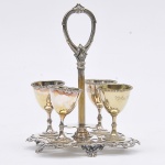 Antigo conjunto para licor em metal espessurado a prata ricamente cinzelado composto por base trabalhada em vazado com pés dito "Garra" e quatro tacinhas decorada com perolados. Med: 22cm (Total)  e 7cm (Taças)