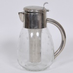 Bela Refresqueira confeccionada em cristal no tom translúcido lapidado com estrelas e com guarnição em metal espessurado a prata. Med: 26cm