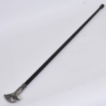 Bengala confeccionada em fibra de carbono com castão com lâmina removível em metal ricamente cinzelado representando "Cabeça de Águia" com ponteira em borracha. Med: 91cm