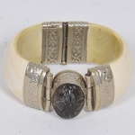 Antiga pulseira confeccionada em marfim oriental com aplicações em metal espessurado a prata cinzelado e galeria central com pedra sintética. med: 8cm