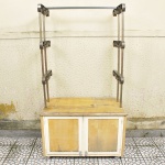 Armário prateleira com rodinhas confeccionado em madeira, parte inferior com duas portas e aplicações em metal patinado, Parte superior com estrutura em metal para 3 prateleiras com terminações recurvas. Med: 188 x 118 x 65cm (No Estado)