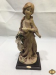 Escultura de menina com cacho de uvas em resina italiana assinado Giuseppe Armani. Medindo 21,5cm de altura.