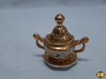 Miniatura de açucareiro em porcelana trabalhada com relevos floral com ouro. Medindo 8cm de altura.