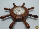 Relógio de parede na forma de timão com maquinário à corda da marca Rubinick. Medindo o timão 32,5cm de diâmetro.