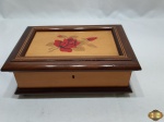 Caixa retangular em madeira marchetada, com interior em veludo. Medindo 23,5cm x 17cm x 9,5cm de altura. Com tranca, porém não acompanha a chave.