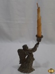 Castiçal na forma de anjo em metal prateado com relevos. Medindo 23cm de altura.