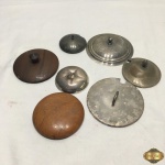 Lote de 7 tampas em materiais diversos. Medindo a maior 11,5cm de diâmetro.
