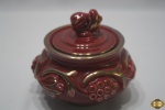 Potiche em porcelana vinho com ouro, trabalhada com relevos. Medindo 13cm de diâmetro de bojo x 8,5cm de altura.