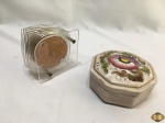 Lote composto de caixa em porcelana e 6 porta copos em acrílico com fundo em cortiça. Medindo a caixa 13cm de diâmetro x 5,5cm de altura.