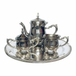Elegante e antigo mini conjunto banhado a prata para café, estilo Inglês, rematados  com volutas e folhas de acanto em alto relevo. Total de 4 peças nunca usados. Acompanha caixa original. Presença de pequenas manchas do tempo. Exemplares em excelente estado de conservação.  Dimensões:  Bandeja 25 cm  diâmetro, bule para café 13,5 cm x 17 cm capacidade  150 ml, açucareiro 8,5 cm x 11,5 cm  capacidade 50 g e cremeira 6 cm x 9 cm capacidade 50 ml.