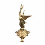 Elegante estatueta em metal maciço, revestido de dourado representando figura feminina com asas, inclinada prestes a alçar voo, ostentando coroa Triunfal. Base rematada em folhas de acanto e estilizados, apoiada por três pés no formato de patas de leão.  Exemplar antigo e em excelente estado de conservação. Dimensões: 24 cm x 13 cm x 13 cm.