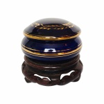 Antigo porta-joias em fina porcelana azul cobalto, decorado com faixa vegetalista e filetes pintados à Ouro. Acompanha base em madeira talhada. Exemplar em excelente estado. Dimensões: 8 cm altura x 8 cm diâmetro.