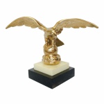 Grandiosa e bela Águia em metal revestido de dourado apoiada sobre base construída em baquelite. Apresenta pequeno bicado no canto da base. Exemplar antigo e em excelente estado. Dimensões: 22 cm x 32 cm x 14 cm.