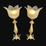 Elegante e robusto par de luminárias construídas em bronze. Bases rematadas com arabescos, apoiadas por 4 pés curtos. Hastes  com efeito retorcido encimada por cúpulas brancas satinadas no formato de flor. Exemplar antigo, possivelmente anos 30 e em excelente estado de conservação. Fiação nova , acompanha lâmpadas. Dimensões: 42 cm x 20 cm. Peso: 6 Kg.