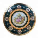 Medalhão em fina porcelana na cor verde esmeralda, com imagem galante no requinte Luís XV ao centro. Arabescos e florões pintados à Ouro em toda a superfície, embelezam o exemplar. Assinado e com selo de manufatura no fundo. Dimensões: 27 cm de diâmetro.A marca de decoração de porcelana Luiz XV  e esteve presente no Brasil dos anos 1940 (após a segunda guerra) até 1970. Esta decoração era executada pelo próprio grupo Schmidt (Schmidt, Real e Steatita), que comprou os direitos de reprodução de padrões de decoração da Europa para uso no Brasil, em peças de sua própria fabricação.