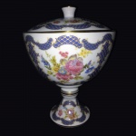 Elegante bomboniere em fina porcelana anos 50. Fundo branco, bojudo, decorado com imagens de galerias e rosas. Borda, base e pega pintados à Ouro.Exemplar antigo e em perfeito estado de conservação.Dimensões: 24 cm altura x 19 cm diâmetro.