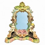 Cerâmica Tasca - Grandioso e antigo espelho de mesa em cerâmica esmaltada e vitrificada, anos 50, rematado com folhas de acanto, volutas, conchas, ladeado por suntuosos querubins. Acompanha espelho. Exemplar raro e em excelente estado de conservação. Inscrição " Tasca 216 K." Imperceptível restauro no braço do querubim à esquerda. Dimensões: 46 cm x 44 cm x 14 cm.