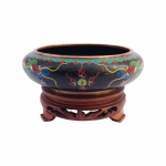 Antigo e belo bowl Cloisonné , de origem  Oriental, rematado com imagens de Dragões sobre fundo preto. Exemplar possivelmente final séc 19 e em excelente  estado de conservação. Acompanha peanha em madeira talhada e envernizada. Dimensões: 8 cm x 14 cm .