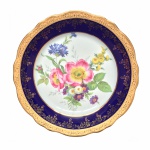 Limoges - Excepcional Medalhão de coleção em fina porcelana Francesa, anos 50, decorado com Flores do campo ao centro. Borda ondulada exibindo larga faixa azul cobalto, rematada com arabescos e estilizados pintados à Ouro 22k. Selos de autenticidade no verso. Exemplar antigo e em perfeito estado de conservação. Dimensões: 25 cm diâmetro.