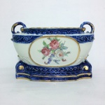 Antiga e suntuosa floreira em porcelana  rematada com arabescos  e largas faixas azul royal. Bojo decorado com ramo de Flores do campo e  baía com embarcações. Alças altas e curtas. Detalhes pintados à Ouro. Manufatura P.S.S Pedreira.  Dimensões: 27 cm x 17 cm x 13 cm.
