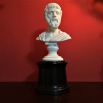 Antigo Busto do Dramaturgo Grego Sófocles construído em pó de mármore sobre base em madeira torneada. Exemplar rico em detalhes e em excelente estado de conservação. Dimensões: 24 cm x 11 cm.