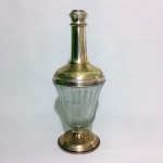 Antiga e robusta garrafa em metal cinzelado e banhado à prata, incrustada com folhas de acanto. Bojo abaulado em Demi cristal com lapidação dito"Bico de Jaca".Exemplar com manchas do tempo e em excelente estado de conservação. Ausência da tampa. Dimensões: 39 cm x 15 cm diâmetro. Capacidade: 1 L.
