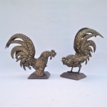 Par de galos em posição de ataque construído em bronze, rico em detalhes, fixados em bases de madeira. Exemplares em excelente estado de conservação. Dimensões: 22 cm x 25 cm x 14 cm e 26 cm x 24 cm x 20 cm.