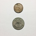 Duas moedas Norte Americanas dos anos de 1944 no valor de 1 cent e de 1969 no valor de quarter dollar. Presença de marcas do tempo.
