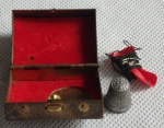 Pequena Caixa de costura  para  viagem em metal dourado, interior forrado em tecido vermelho contendo um dedal e linha. Med. 2 x 3 x 4cm