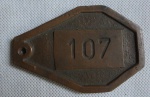 COLECIONISMO - Medalhão de Bronze com numero 107 provavelmente indicativo de quarto de hotel. Comp. 10cm